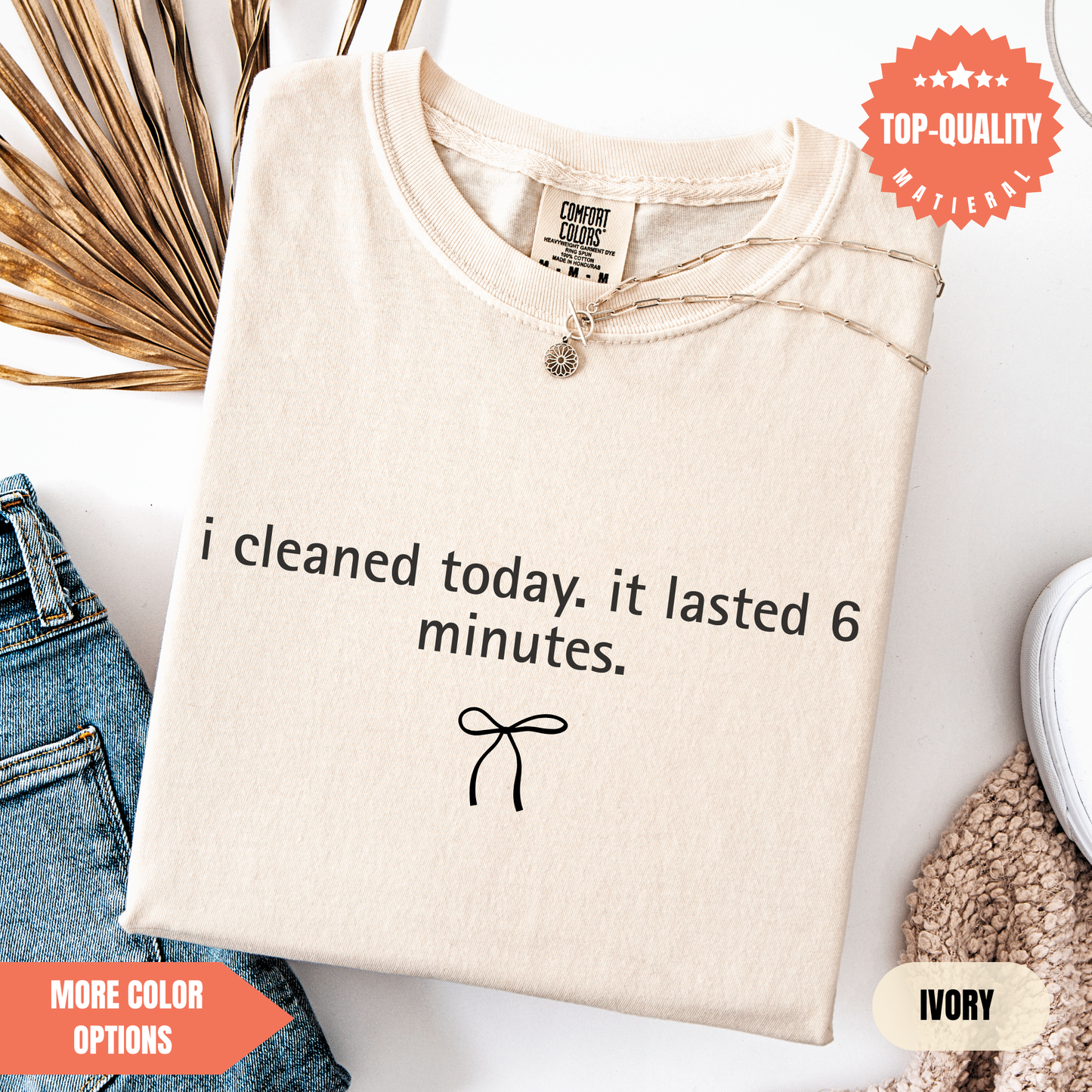 a beige t-shirt with a humorous text printed on it, along with a small bow and some other clothing items.