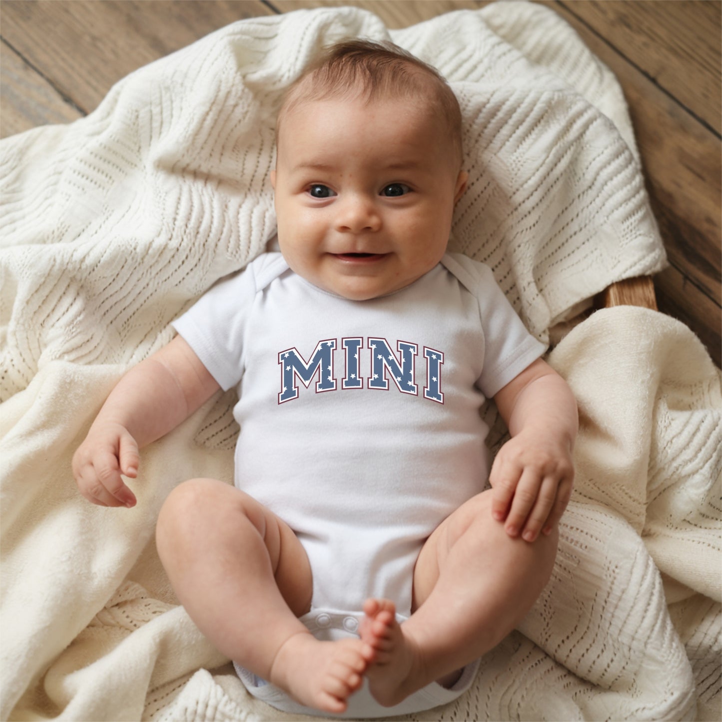a baby sitting on a blanket on a wooden floor