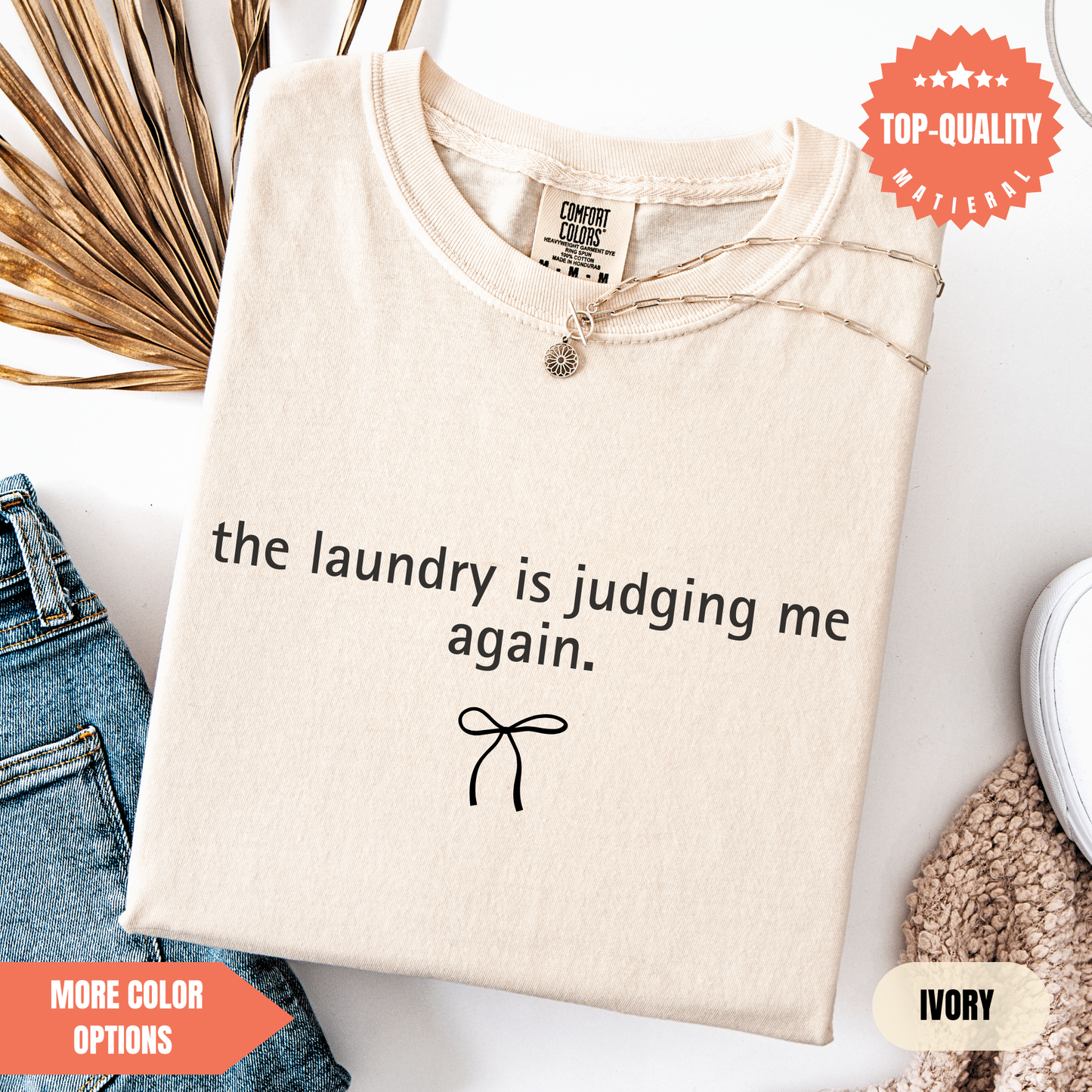 a beige t-shirt with a humorous text printed on it, along with a small bow and some other clothing items.