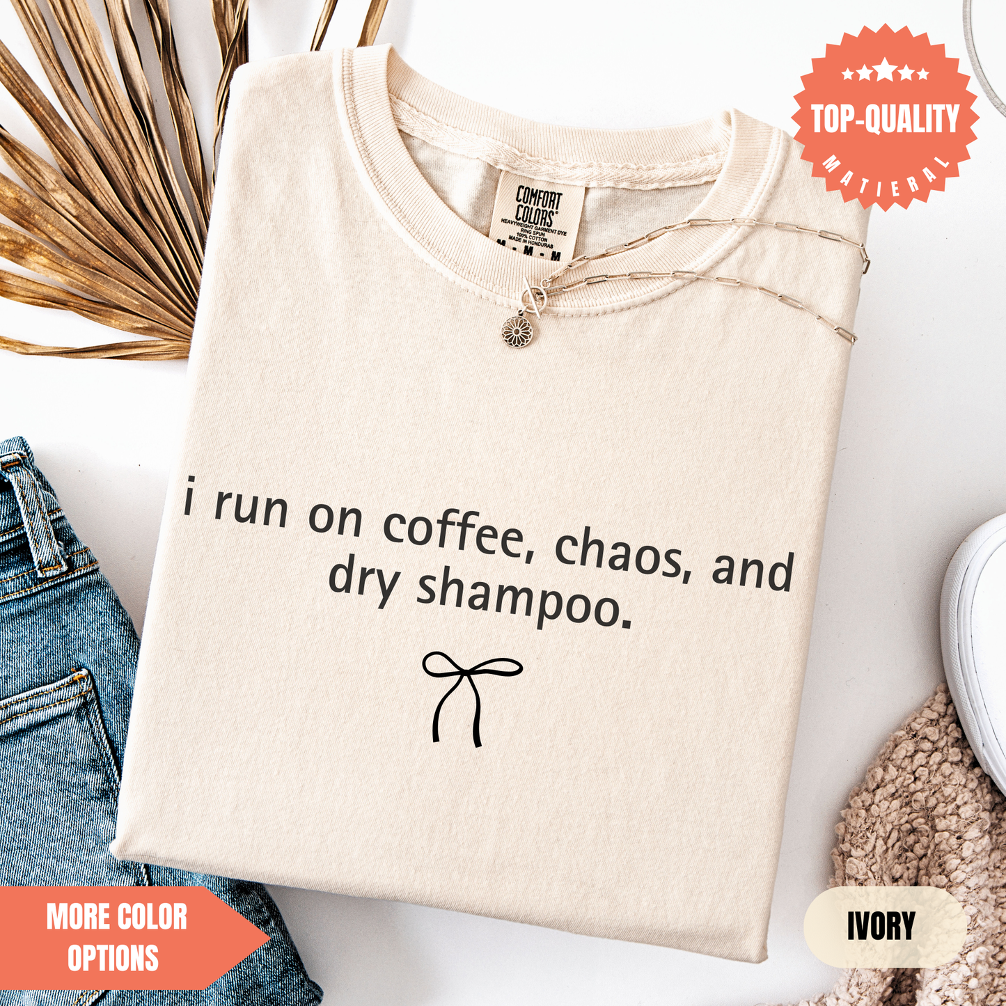 a beige t-shirt with a humorous text printed on it, along with a small bow and some other items such as jeans and a sweater.