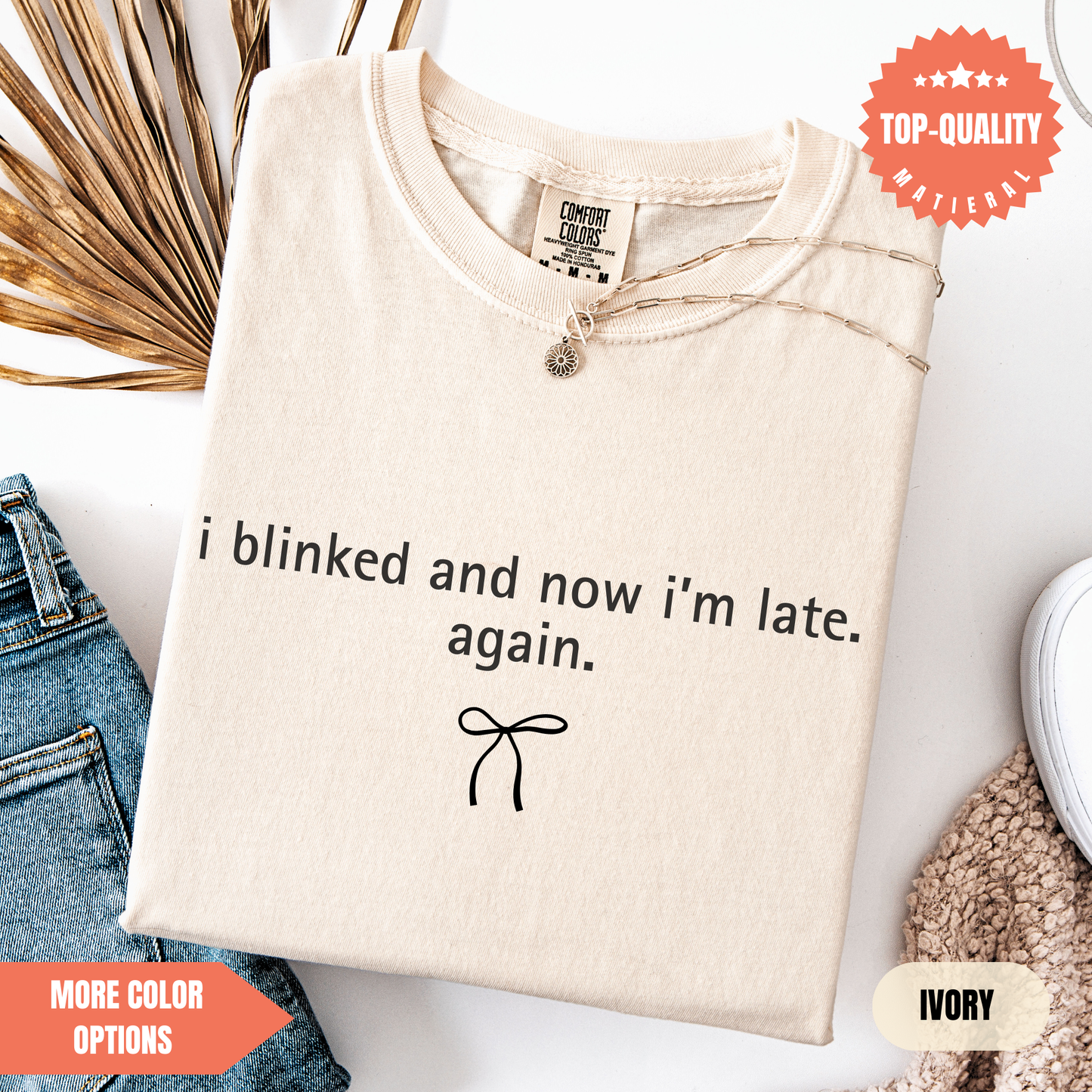 a beige t-shirt with a humorous text printed on it, along with a small bow and some other clothing items.