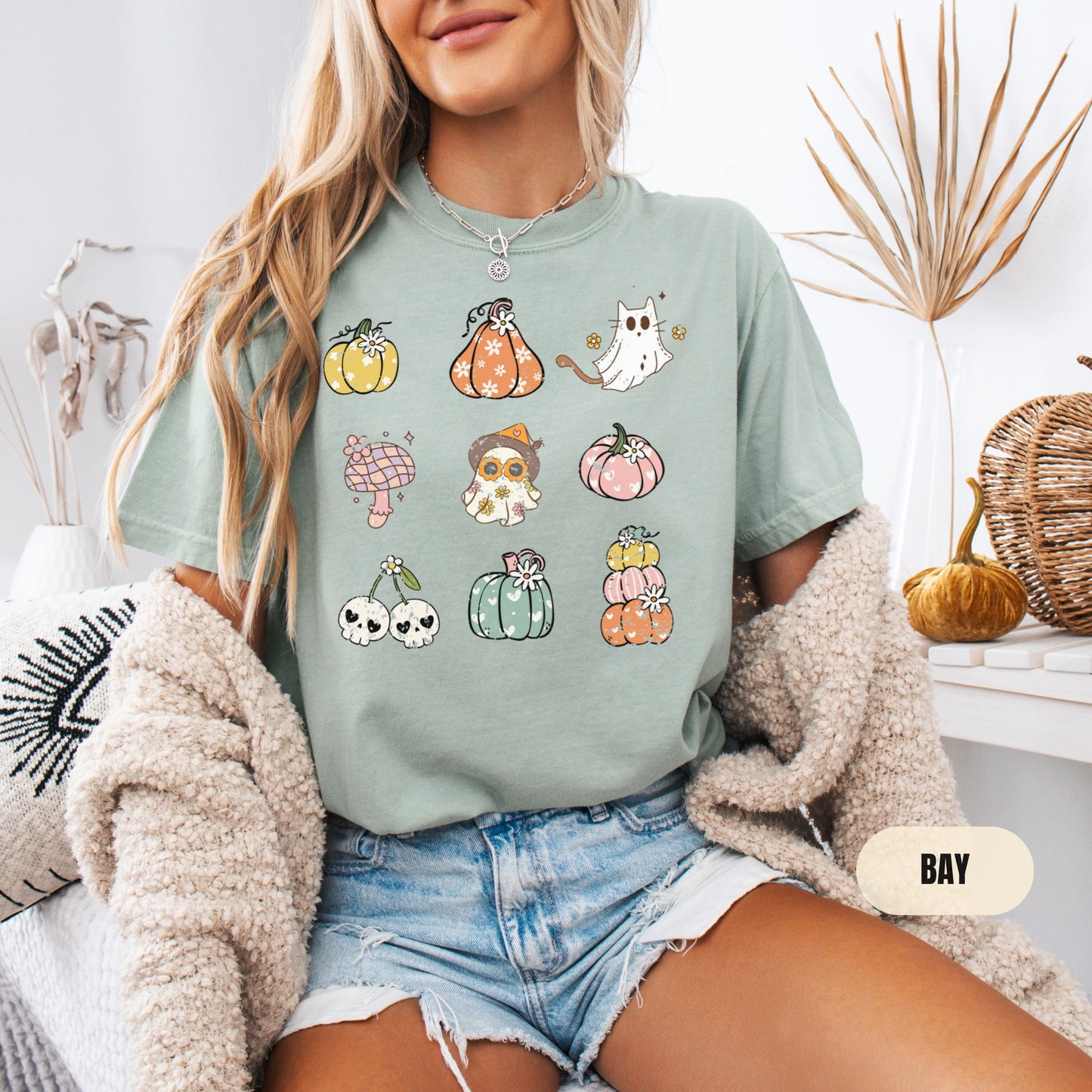 a woman sitting on a bed wearing a t - shirt with a bunch of pumpkin