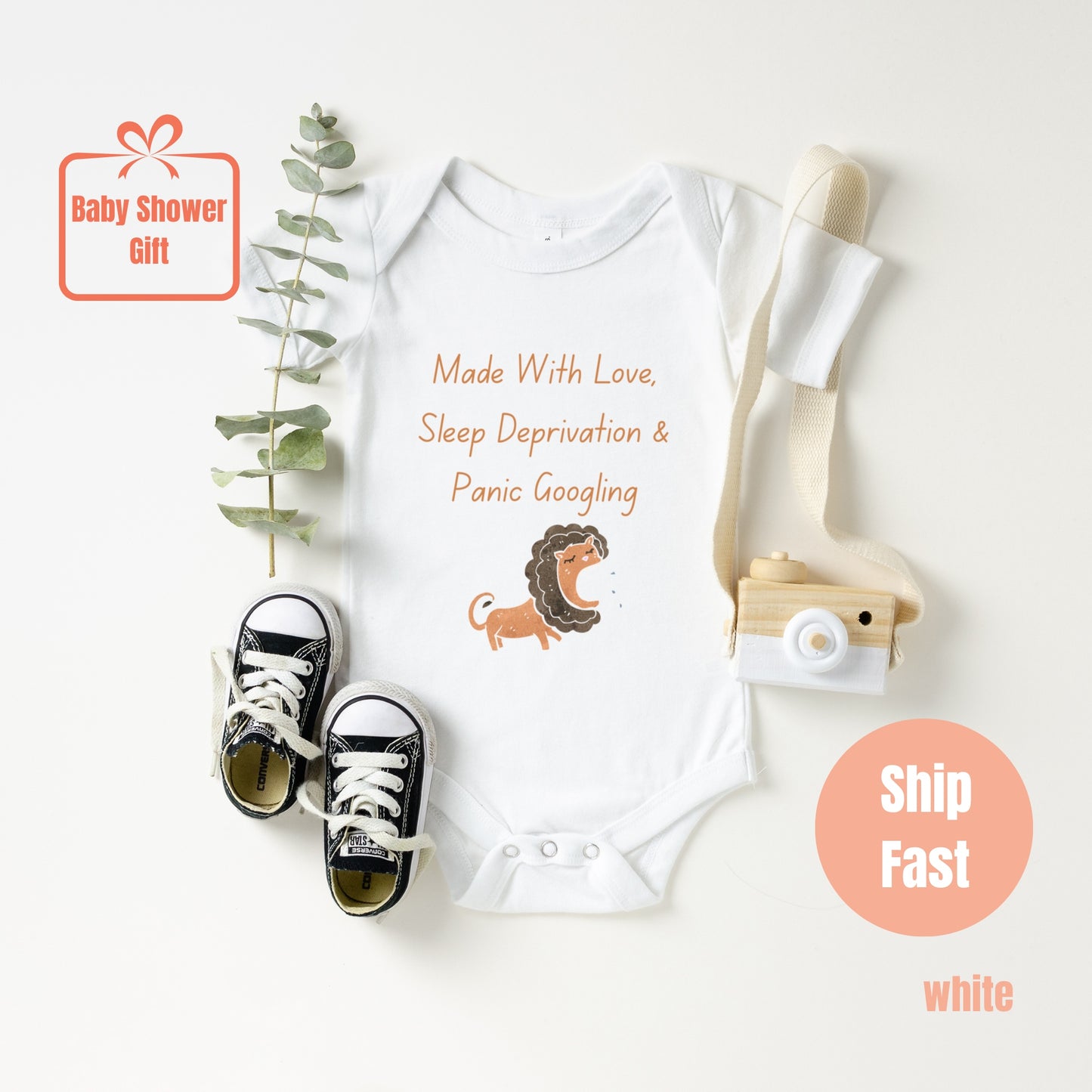 a baby bodysuit with a lion on it next to a pair of sneakers