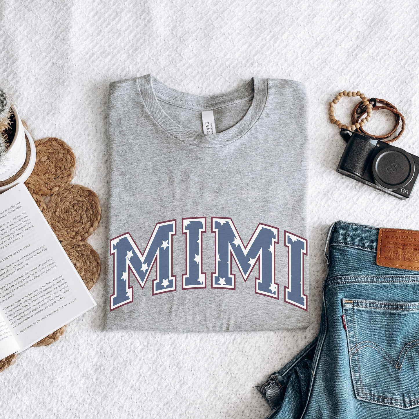 a t - shirt with the word mimi on it next to a pair of jeans