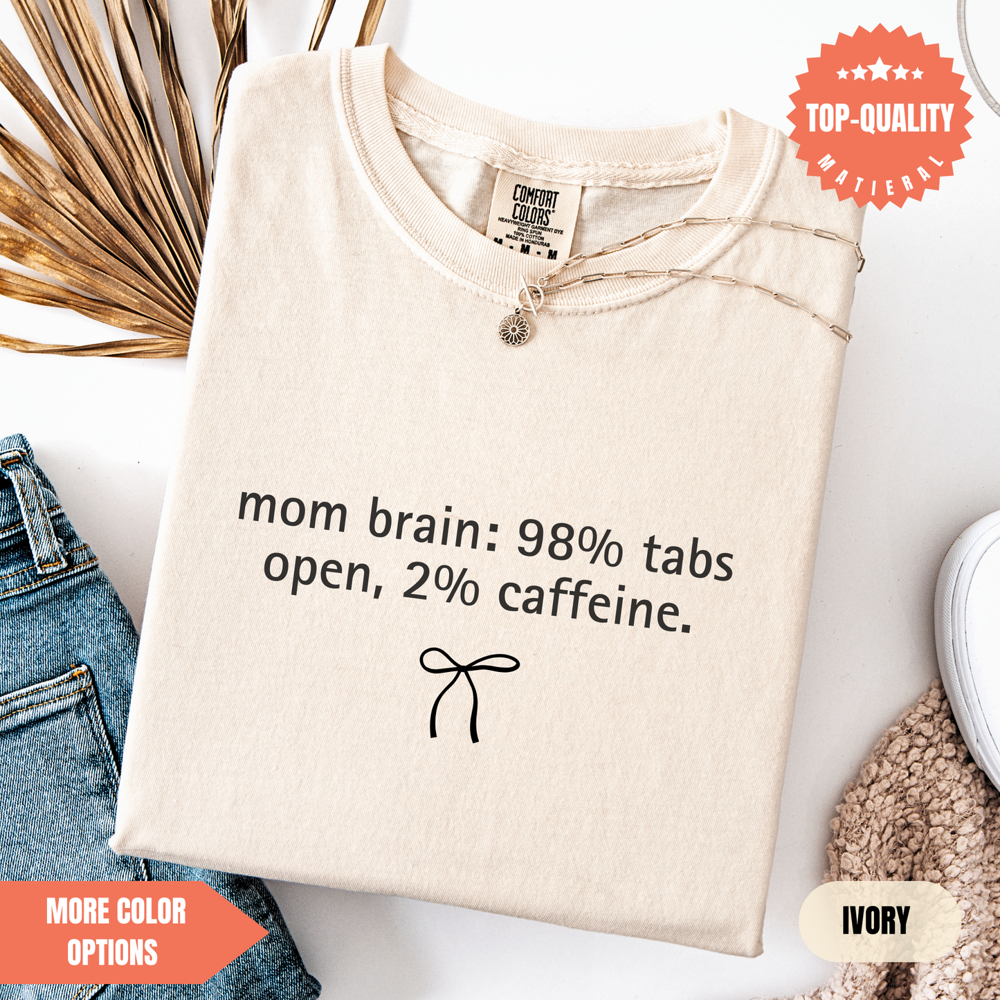 a beige t-shirt with a humorous text printed on it, along with a small bow and some textured fabric.