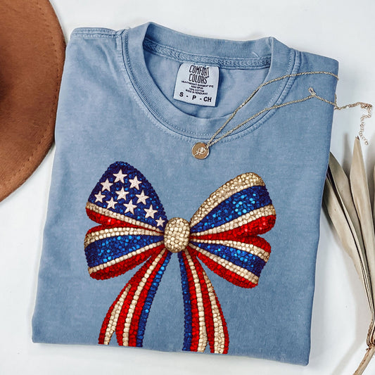 a blue t - shirt with a red, white, and blue bow on it